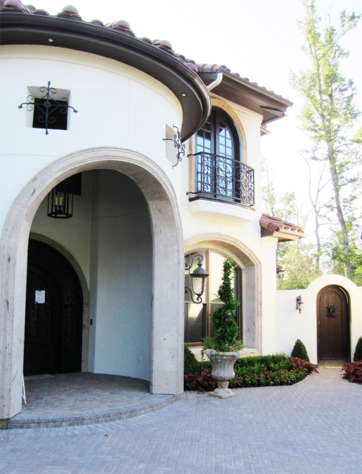 Photo of a mid-sized mediterranean two-storey stucco white house exterior in Houston with a gable roof and a tile roof.