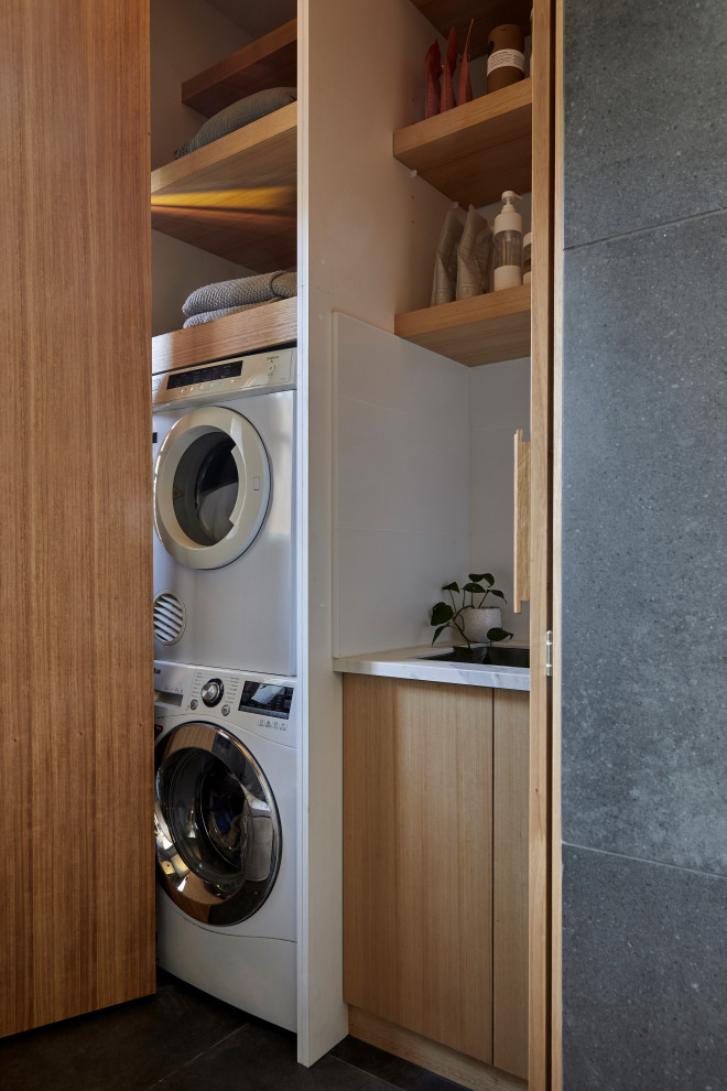 Design ideas for a mid-sized contemporary laundry room in Melbourne with flat-panel cabinets, grey cabinets, multi-coloured walls, porcelain floors, grey floor and vaulted.