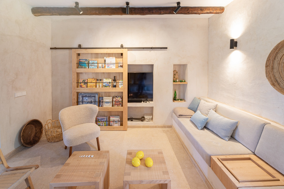 Modelo de salón abierto mediterráneo grande con paredes beige, suelo de travertino, televisor retractable, suelo beige y vigas vistas