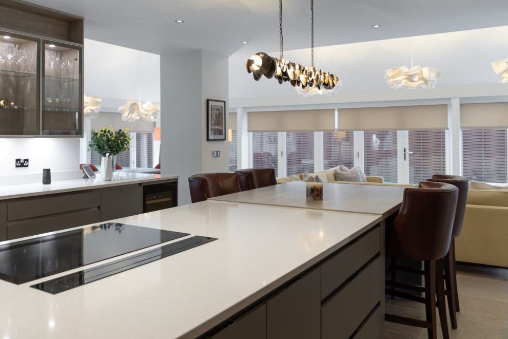 Inspiration for a large contemporary open plan kitchen in London with an undermount sink, flat-panel cabinets, grey cabinets, quartzite benchtops, white splashback, glass sheet splashback, stainless steel appliances, limestone floors, with island, beige floor, white benchtop and vaulted.