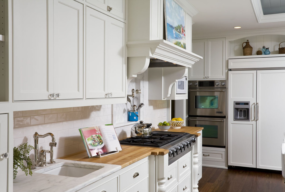 Design ideas for a large traditional l-shaped eat-in kitchen in Minneapolis with shaker cabinets, white cabinets, marble benchtops, white splashback, subway tile splashback, stainless steel appliances, dark hardwood floors, with island and an undermount sink.
