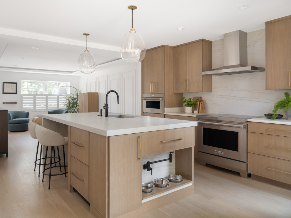 Eat-in kitchen - mid-sized contemporary galley light wood floor, brown floor and tray ceiling eat-in kitchen idea in DC Metro with an undermount sink, flat-panel cabinets, light wood cabinets, quartz countertops, white backsplash, quartz backsplash, stainless steel appliances, an island and white countertops