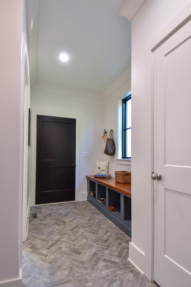 Photo of a small country mudroom in Other with white walls, porcelain floors, a single front door, a black front door and grey floor.