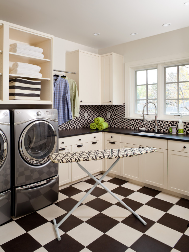Inspiration for a mid-sized traditional l-shaped utility room in Denver with an undermount sink, shaker cabinets, white cabinets, granite benchtops, cement tile splashback, white walls, ceramic floors, a side-by-side washer and dryer and black benchtop.