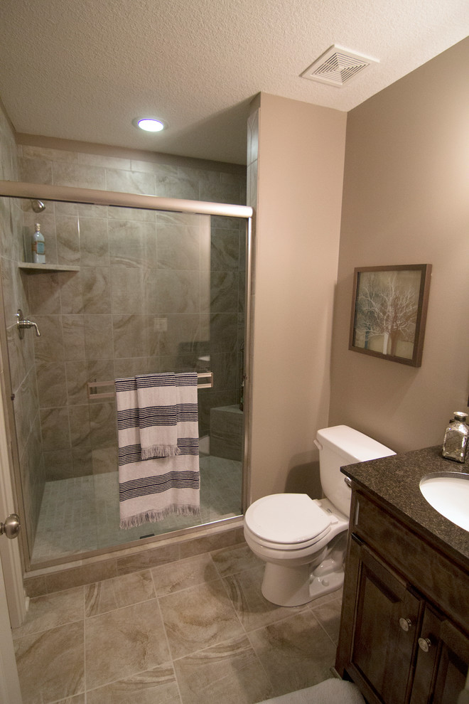 Photo of a mid-sized traditional master bathroom in Kansas City with an undermount sink, dark wood cabinets, white tile, ceramic tile, ceramic floors, beige walls, a two-piece toilet, raised-panel cabinets, an alcove shower and a hinged shower door.
