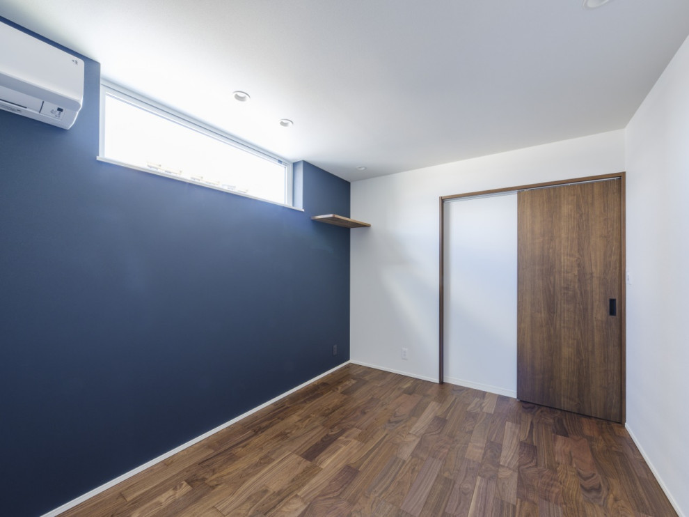 Cette image montre une chambre parentale minimaliste de taille moyenne avec un mur bleu, parquet foncé, un sol marron, un plafond en papier peint et du papier peint.