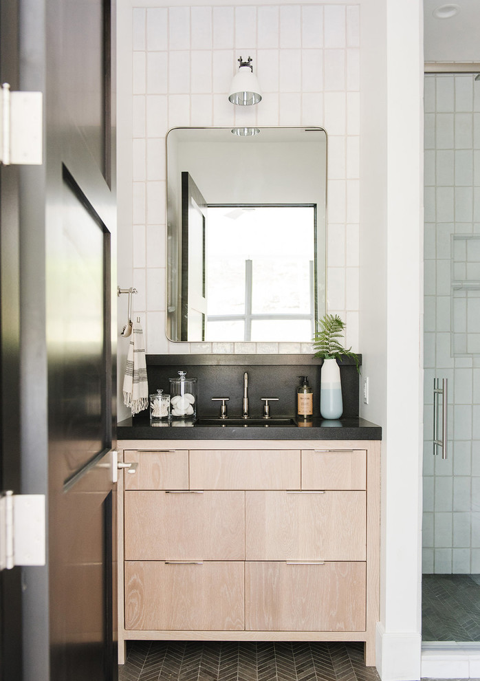 Inspiration for a mid-sized country 3/4 bathroom in Salt Lake City with light wood cabinets, white tile, white walls, a hinged shower door and black benchtops.
