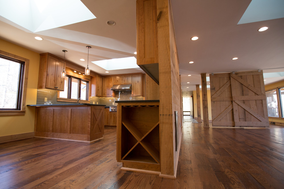 Example of a large mountain style u-shaped dark wood floor kitchen pantry design with a single-bowl sink, raised-panel cabinets, medium tone wood cabinets, blue backsplash, ceramic backsplash, stainless steel appliances and no island