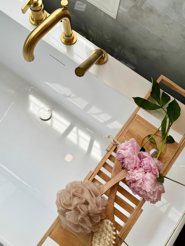 Organic Modern bathroom design in Rockville, MD featuring a spa-like atmosphere with large-format porcelain tile, natural wood vanities, and minimalist black hardware. This primary bath renovation by
