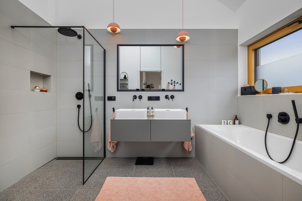 Badezimmer With flächenbündigen Schrankfronten, grauen Schränken, Badewanne in Nische, bodengleicher Dusche, grauen Fliesen, weißer Wandfarbe, Aufsatzwaschbecken, grauem Boden, offener Dusche, grauer Waschtischplatte, Doppelwaschbecken, schwebendem Waschtisch and gewölbter Decke in Munich