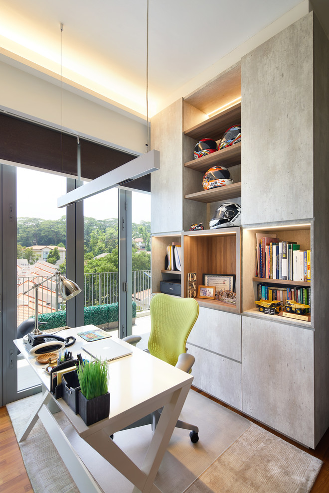 Eclectic home office in Singapore with white walls, medium hardwood floors, a freestanding desk and brown floor.