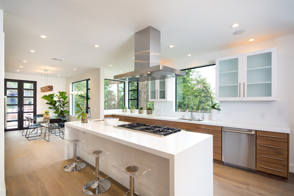 Photo of a contemporary galley eat-in kitchen in DC Metro with an undermount sink, flat-panel cabinets, medium wood cabinets, white splashback, stainless steel appliances, light hardwood floors, with island, beige floor and white benchtop.