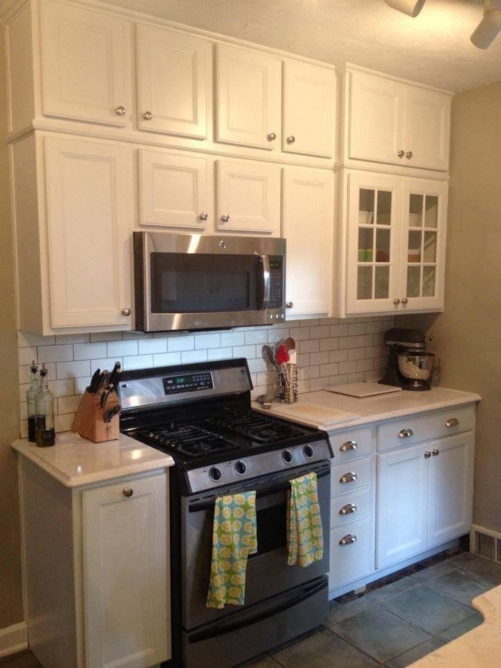This is an example of a small traditional galley separate kitchen in Indianapolis with a farmhouse sink, recessed-panel cabinets, white cabinets, quartzite benchtops, white splashback, ceramic splashback, stainless steel appliances and ceramic floors.