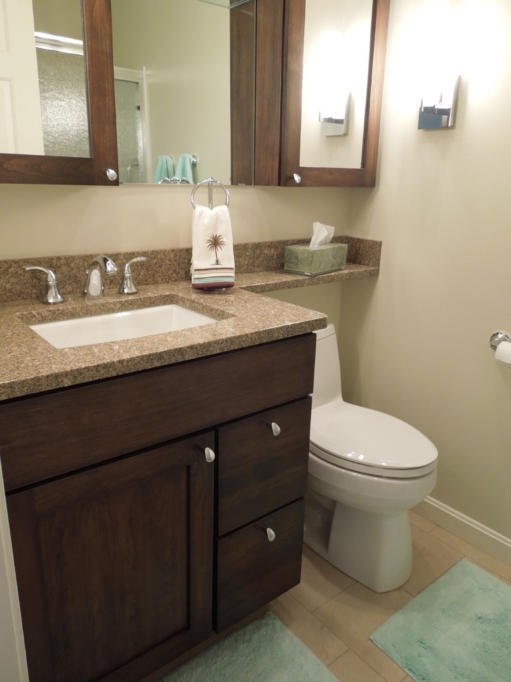 Photo of a small transitional bathroom in Charleston with an undermount sink, dark wood cabinets, granite benchtops, an alcove tub, a shower/bathtub combo, a one-piece toilet, beige tile, porcelain tile, beige walls and porcelain floors.