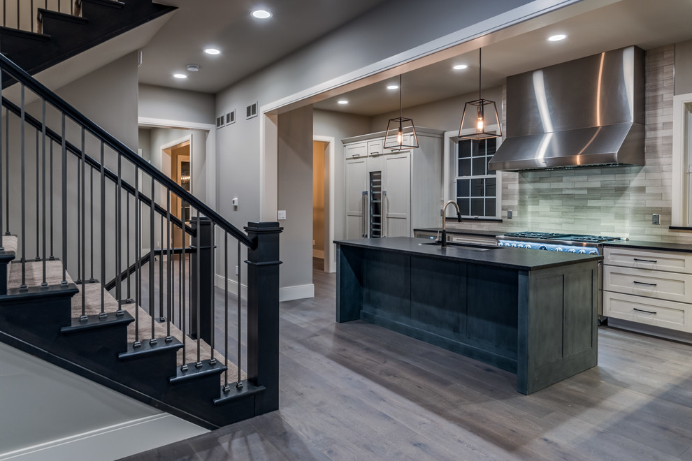 Mid-sized transitional l-shaped dark wood floor and gray floor open concept kitchen photo in Denver with an undermount sink, shaker cabinets, white cabinets, granite countertops, gray backsplash, stone tile backsplash, stainless steel appliances, an island and black countertops