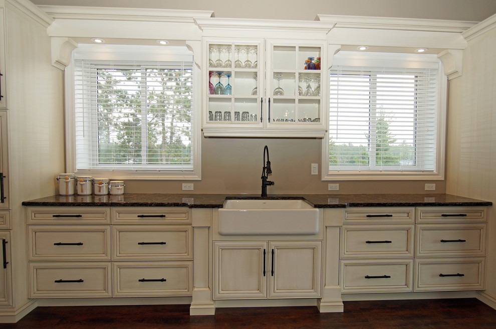 Large mountain style galley kitchen photo with a farmhouse sink, recessed-panel cabinets, white cabinets, quartzite countertops, stainless steel appliances and brown countertops