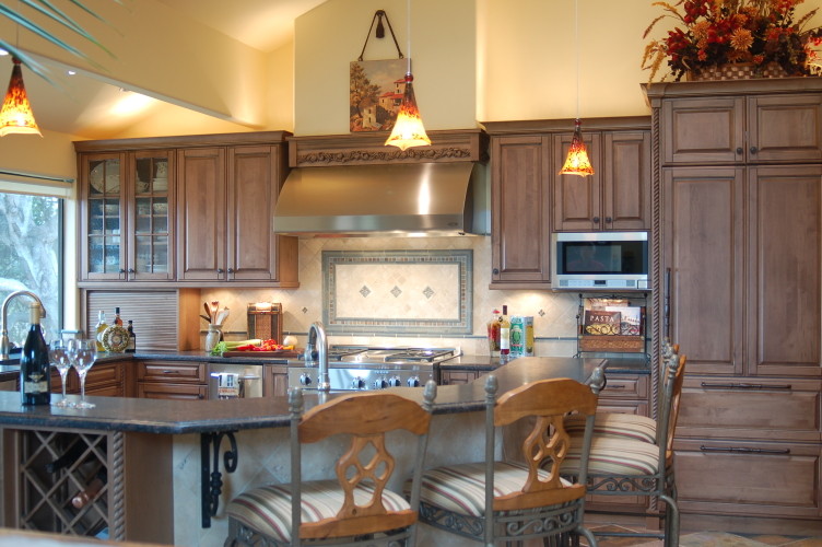 Example of a classic u-shaped open concept kitchen design in San Luis Obispo with an undermount sink, raised-panel cabinets, distressed cabinets, granite countertops, multicolored backsplash, stone tile backsplash and stainless steel appliances