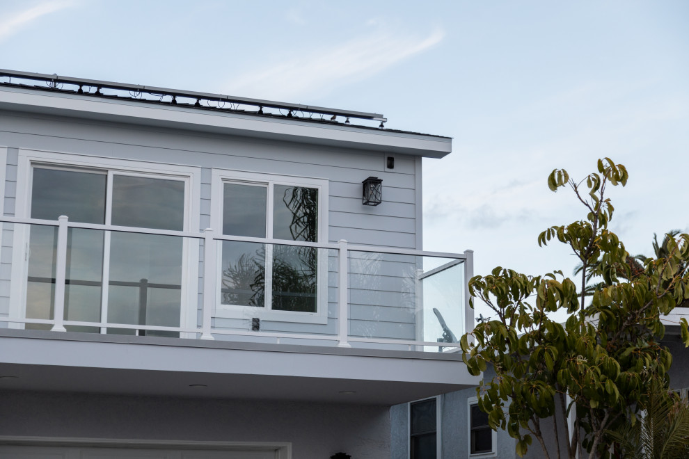Cette photo montre une petite façade de maison grise bord de mer en bardage à clin à un étage avec un revêtement mixte, un toit à deux pans, un toit en shingle et un toit gris.