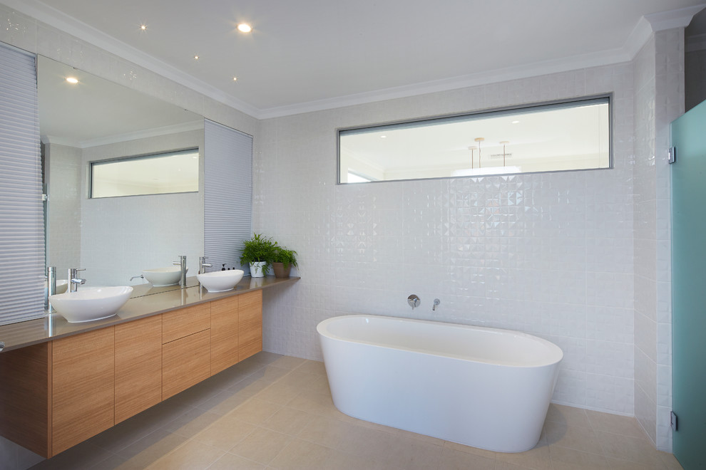 This is an example of a mid-sized contemporary master bathroom in Perth with a vessel sink, medium wood cabinets, a freestanding tub, beige tile and white walls.