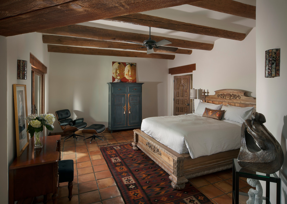 This is an example of a mid-sized country master bedroom in Phoenix with white walls and terra-cotta floors.