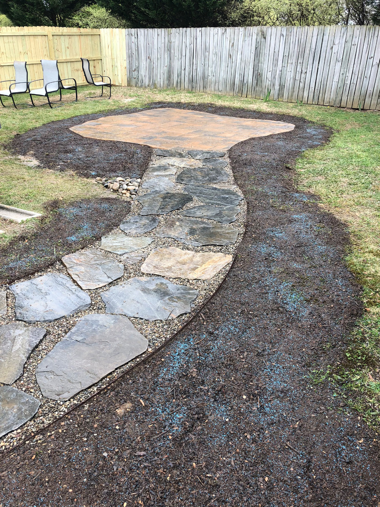 Photo of a mid-sized traditional backyard full sun garden for summer in Charlotte with natural stone pavers.