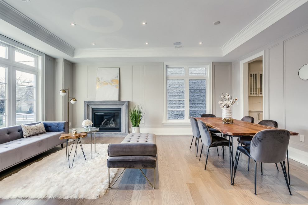 This is an example of a transitional formal open concept living room in Toronto with grey walls, light hardwood floors, a standard fireplace, no tv, beige floor, recessed and panelled walls.