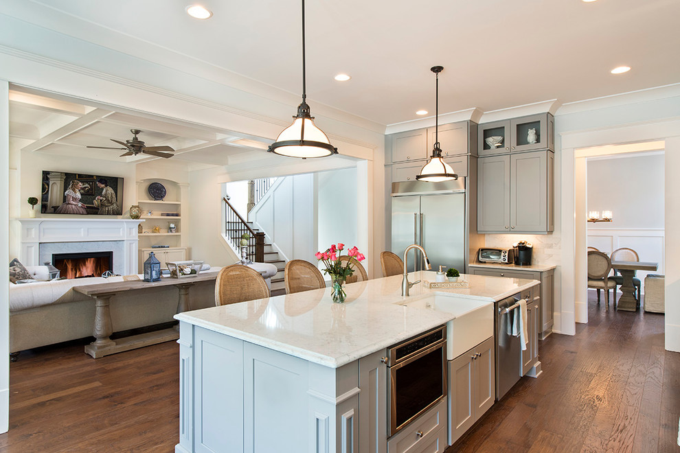 Design ideas for a large transitional l-shaped open plan kitchen in Atlanta with a farmhouse sink, recessed-panel cabinets, grey cabinets, white splashback, ceramic splashback, stainless steel appliances, medium hardwood floors, with island and granite benchtops.