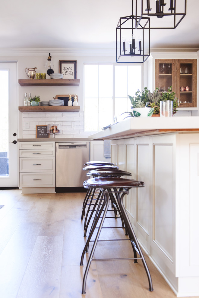 Photo of a mid-sized transitional l-shaped open plan kitchen in San Diego with an undermount sink, recessed-panel cabinets, white cabinets, quartzite benchtops, multi-coloured splashback, cement tile splashback, stainless steel appliances, light hardwood floors, with island and beige floor.