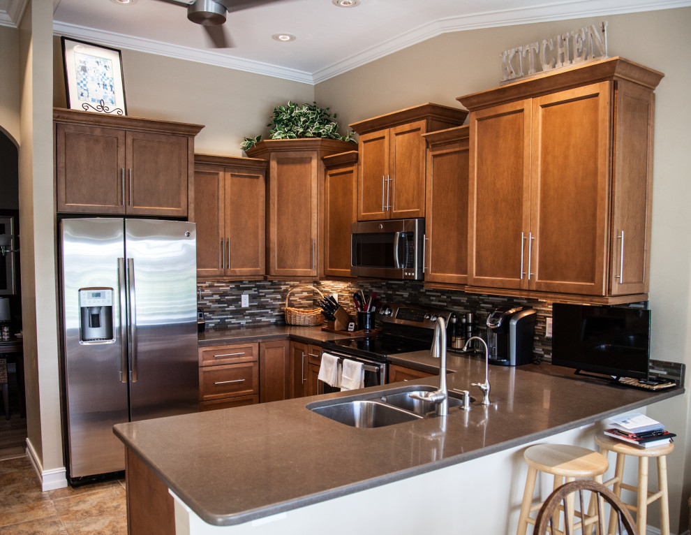 Photo of a mid-sized u-shaped kitchen in Other with an undermount sink, shaker cabinets, brown cabinets, wood benchtops, mosaic tile splashback, stainless steel appliances, ceramic floors, brown benchtop and vaulted.