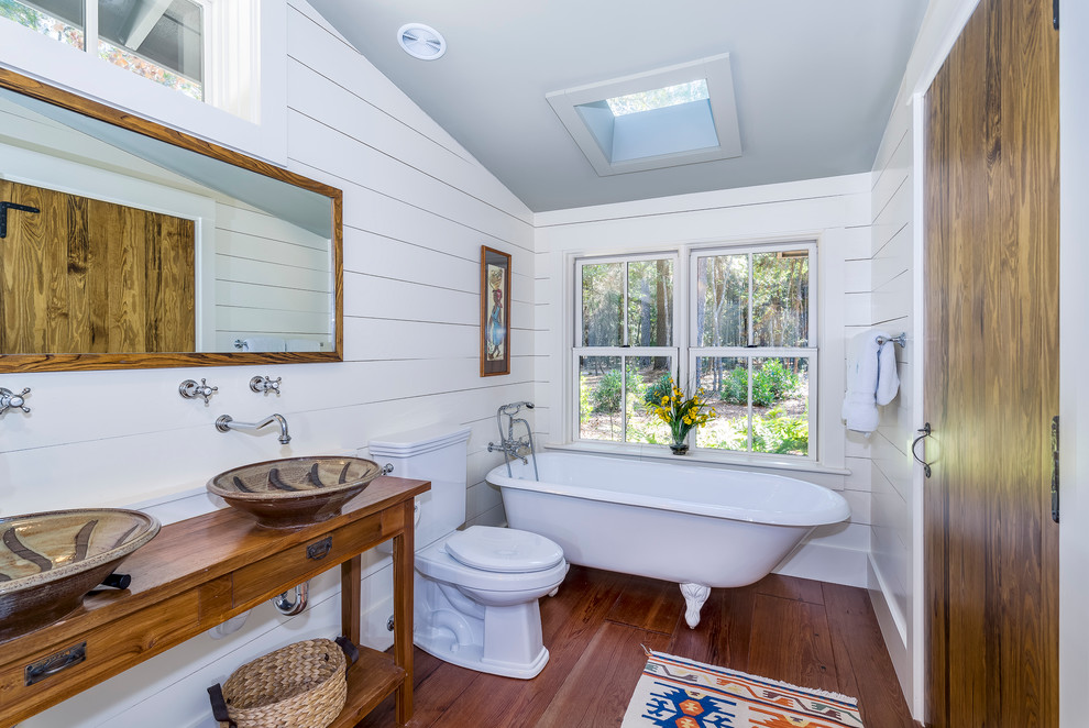 Inspiration for a country bathroom in Atlanta with a vessel sink, medium wood cabinets, wood benchtops, a claw-foot tub, a two-piece toilet, white walls, dark hardwood floors and open cabinets.