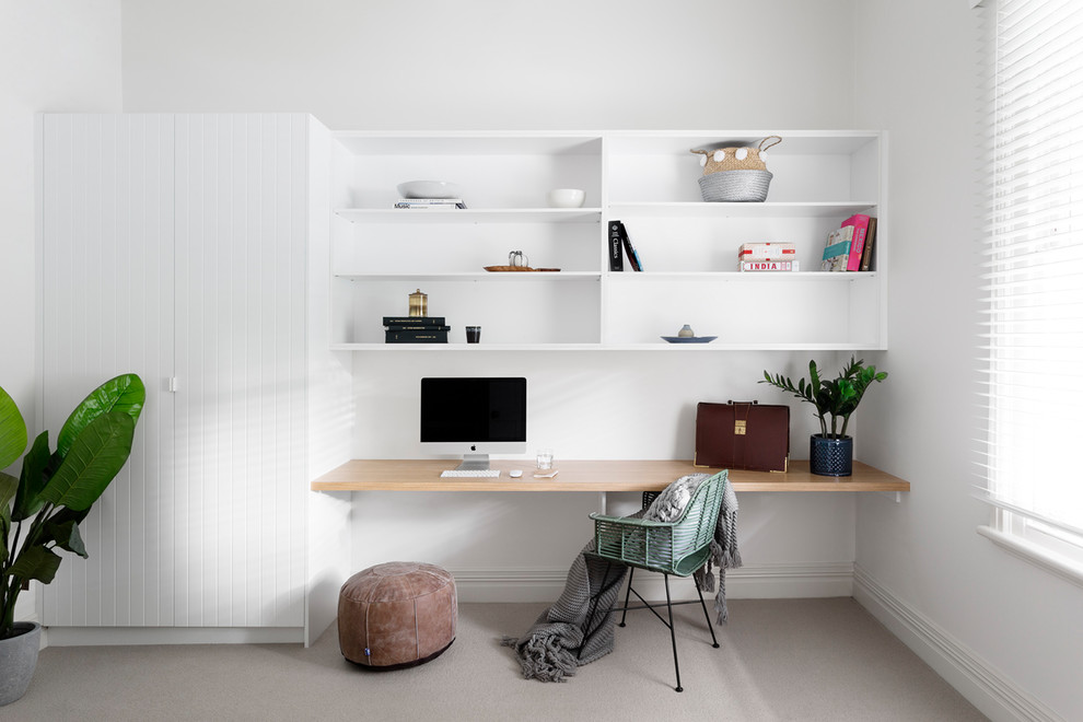 Photo of a mid-sized contemporary home office in Melbourne with white walls, carpet, a built-in desk, beige floor and a library.