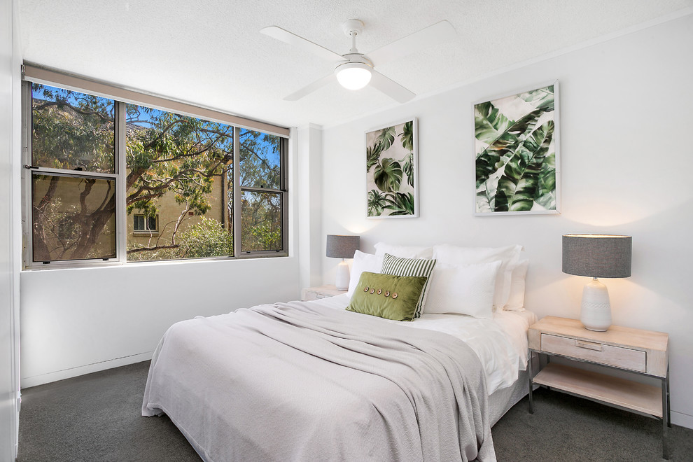 This is an example of a beach style guest bedroom in Sydney with white walls, carpet and grey floor.