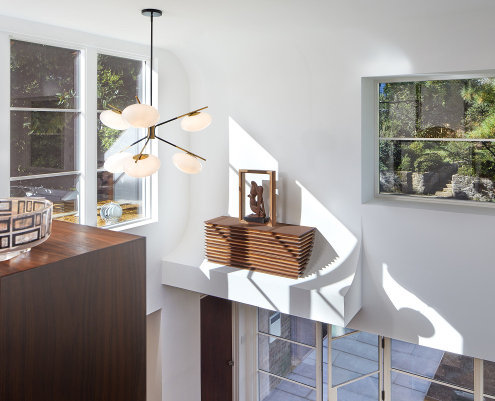 Medium sized modern mezzanine bedroom in DC Metro with white walls, medium hardwood flooring and brown floors.