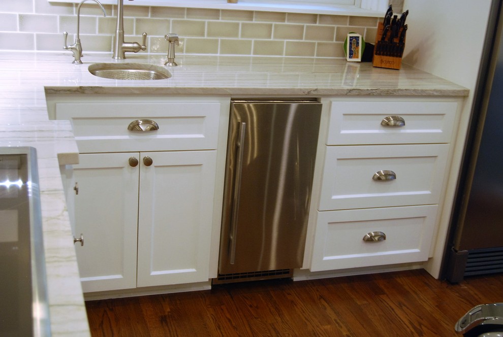 Kitchen - mid-sized transitional u-shaped light wood floor kitchen idea in Austin with a farmhouse sink, shaker cabinets, white cabinets, quartzite countertops, beige backsplash, porcelain backsplash, stainless steel appliances and an island