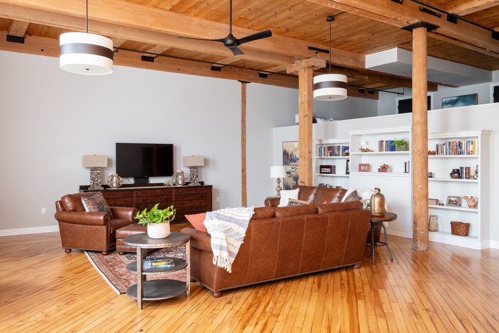 Inspiration for an expansive industrial open concept living room in Boston with a library, light hardwood floors and exposed beam.