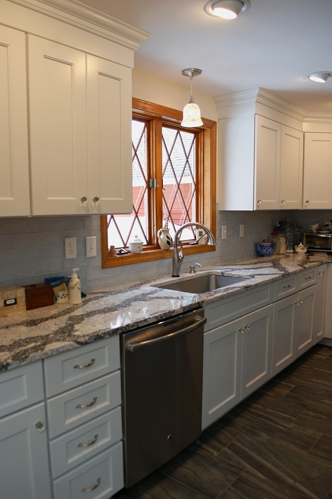 Photo of a large contemporary l-shaped kitchen pantry in Boston with an undermount sink, recessed-panel cabinets, white cabinets, quartz benchtops, blue splashback, glass tile splashback, stainless steel appliances, porcelain floors, with island and grey floor.