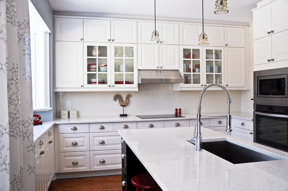 Inspiration for a transitional eat-in kitchen remodel in Ottawa with an undermount sink, raised-panel cabinets, white cabinets, quartz countertops, white backsplash, porcelain backsplash, stainless steel appliances and an island
