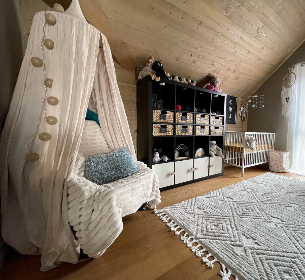 Modelo de habitación de bebé niña tropical de tamaño medio con paredes beige, suelo de madera oscura, suelo marrón, madera y papel pintado