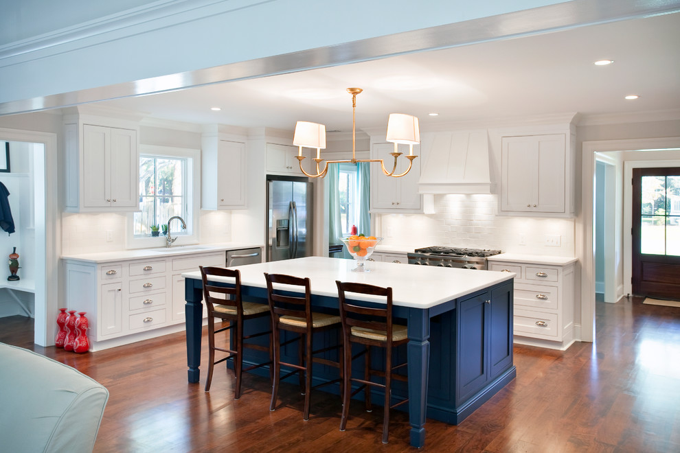 Traditional l-shaped open plan kitchen in San Francisco with recessed-panel cabinets, white cabinets, white splashback, subway tile splashback and stainless steel appliances.