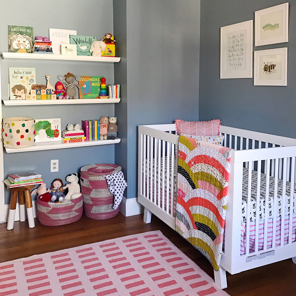 Photo of a mid-sized scandinavian nursery for girls in New York with grey walls and medium hardwood floors.