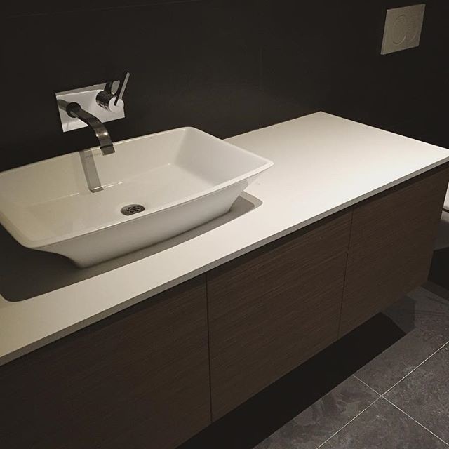 Inspiration for a mid-sized transitional 3/4 white tile ceramic tile bathroom remodel in Toronto with flat-panel cabinets, dark wood cabinets, black walls, a vessel sink and solid surface countertops
