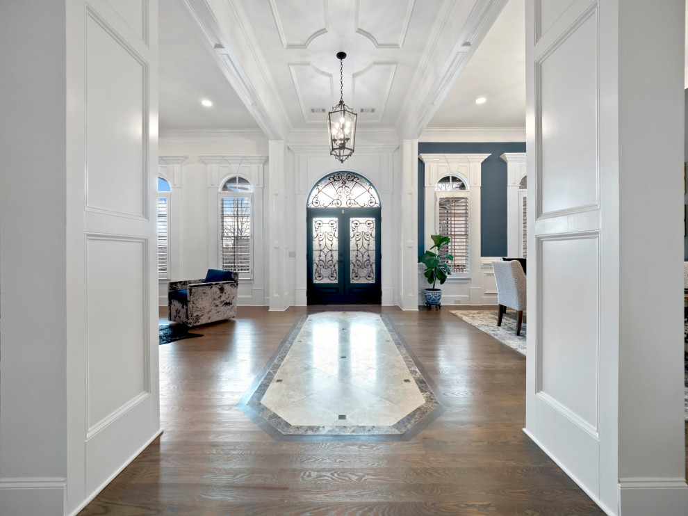 Großes Klassisches Foyer mit beiger Wandfarbe, braunem Holzboden, Doppeltür, brauner Haustür, grauem Boden, gewölbter Decke und Tapetenwänden in Sonstige