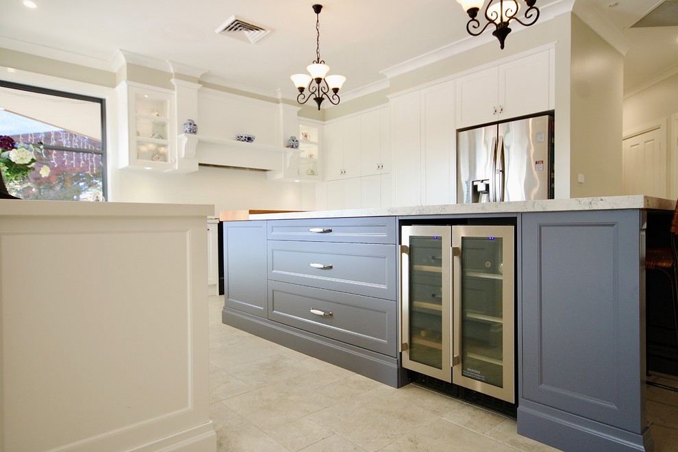Mid-sized transitional u-shaped eat-in kitchen in Sydney with a farmhouse sink, shaker cabinets, white cabinets, quartz benchtops, white splashback, porcelain splashback, stainless steel appliances, porcelain floors, with island and beige floor.