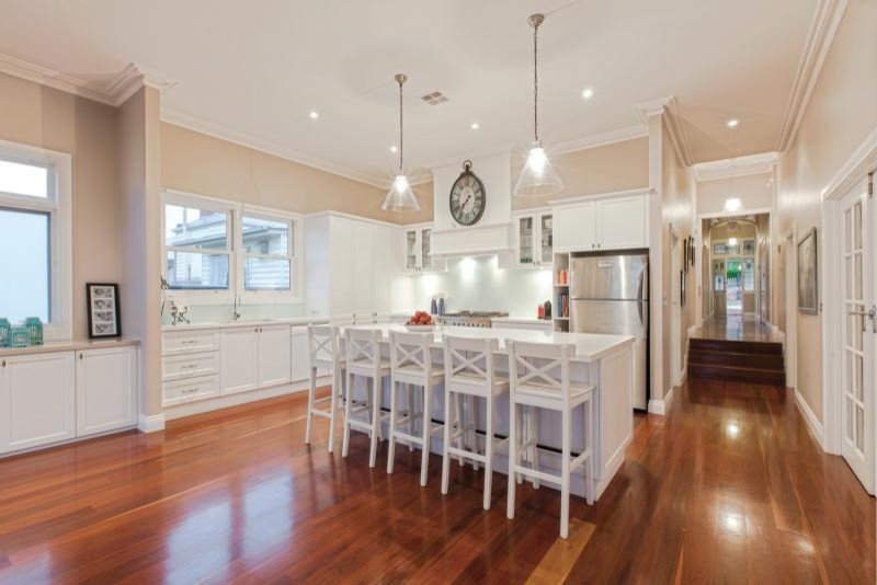 This is an example of a transitional kitchen in Melbourne with recessed-panel cabinets, quartz benchtops, glass sheet splashback, beige walls, medium hardwood floors and with island.