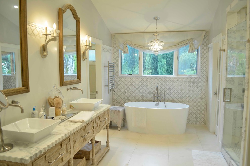 Transitional white tile and stone tile freestanding bathtub photo in Orange County with a vessel sink and marble countertops