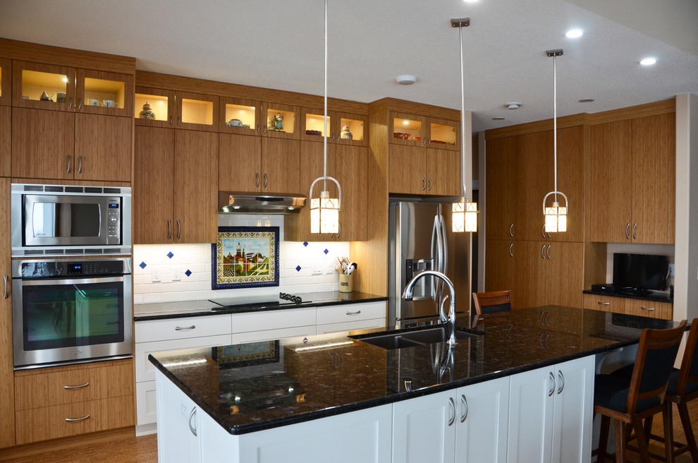 Large transitional single-wall cork floor open concept kitchen photo in Edmonton with an undermount sink, flat-panel cabinets, medium tone wood cabinets, granite countertops, white backsplash, ceramic backsplash, stainless steel appliances and an island