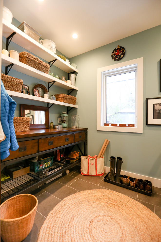 Photo of a mid-sized transitional single-wall utility room in Other with open cabinets, white cabinets, wood benchtops, blue walls, porcelain floors, a side-by-side washer and dryer, grey floor and brown benchtop.