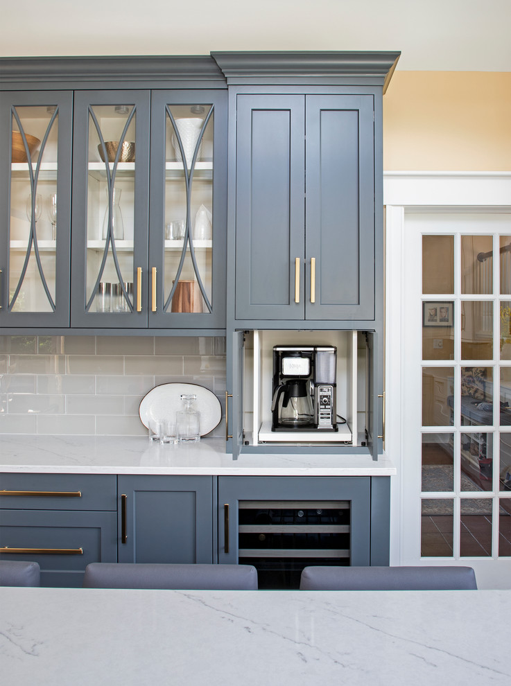 Large transitional u-shaped medium tone wood floor kitchen photo with an undermount sink, gray cabinets, quartz countertops, gray backsplash, glass tile backsplash, paneled appliances, an island and white countertops