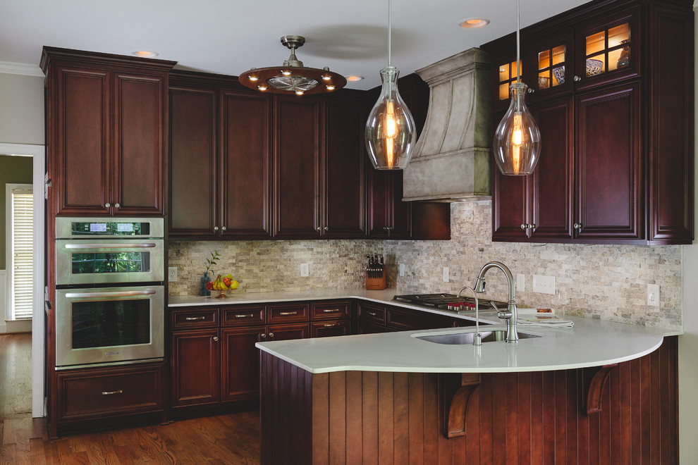 Eat-in kitchen - large transitional u-shaped medium tone wood floor eat-in kitchen idea in Atlanta with an undermount sink, raised-panel cabinets, dark wood cabinets, quartz countertops, gray backsplash, stone tile backsplash, stainless steel appliances and no island