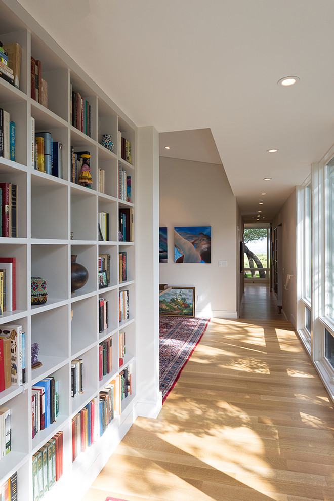This is an example of a mid-sized transitional hallway in Austin with white walls and light hardwood floors.
